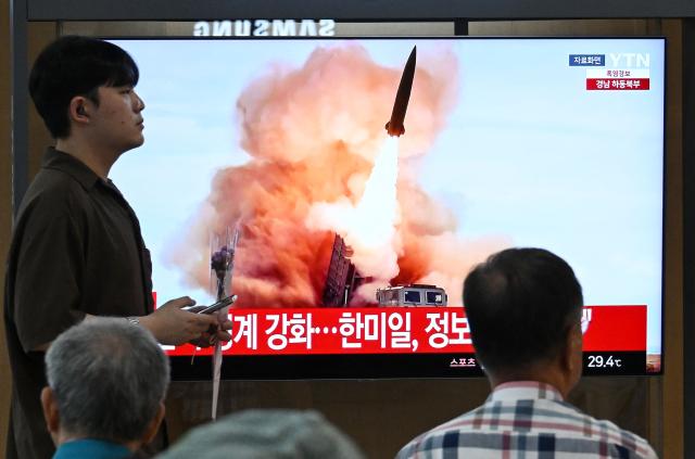 People watch a television screen showing a news broadcast with file footage of a North Korean missile test, at a train station in Seoul on August 20, 2026. North Korea fired around 10 short-range ballistic missiles, South Korea's military said on August 20, hours after US President Donald Trump said he would meet Pyongyang's leader Kim Jong Un later this year. (Photo by Jung Yeon-je / AFP)