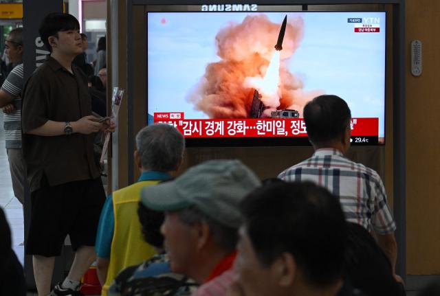 People watch a television screen showing a news broadcast with file footage of a North Korean missile test, at a train station in Seoul on August 20, 2026. North Korea fired around 10 short-range ballistic missiles, South Korea's military said on August 20, hours after US President Donald Trump said he would meet Pyongyang's leader Kim Jong Un later this year. (Photo by Jung Yeon-je / AFP)