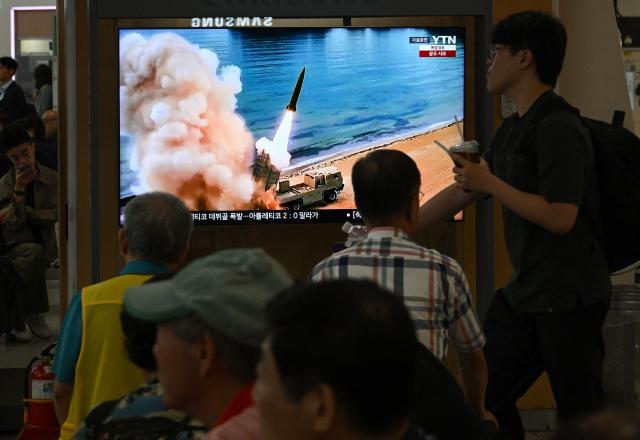People watch a television screen showing a news broadcast with file footage of a North Korean missile test, at a train station in Seoul on August 20, 2026. North Korea fired around 10 short-range ballistic missiles, South Korea's military said on August 20, hours after US President Donald Trump said he would meet Pyongyang's leader Kim Jong Un later this year. (Photo by Jung Yeon-je / AFP)