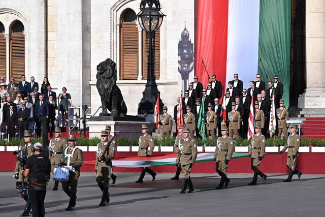 Soldiers march with the national flag during a flag hosting ceremony marking the country's national day attended by guests and ambassadors accredited to Hungary on August 20, 2026, in Budapest. Hungary marks the 1,026th anniversary of the foundation of the Hungarian state, established by the first king of Hungary, Stephen I.  Hungarian President Andras Baka, who took office yesterday, makes his first public appearance since then. (Photo by Attila KISBENEDEK / AFP)