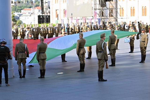 Soldiers prepare the national flag during a flag hosting ceremony marking the country's national day attended by guests and ambassadors accredited to Hungary on August 20, 2026, in Budapest. Hungary marks the 1,026th anniversary of the foundation of the Hungarian state, established by the first king of Hungary, Stephen I.  Hungarian President Andras Baka, who took office yesterday, makes his first public appearance since then. (Photo by Attila KISBENEDEK / AFP)
