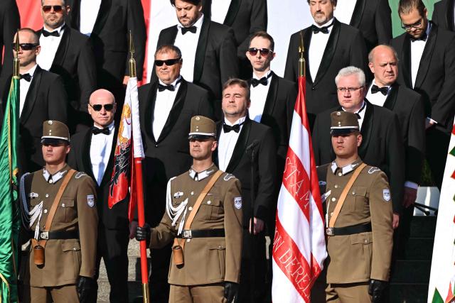 Soldiers stand with the historical Hungarian flags in front of the singers of the choir during a ceremony marking the country's national day attended by guests and ambassadors accredited to Hungary on August 20, 2026, in Budapest. Hungary marks the 1,026th anniversary of the foundation of the Hungarian state, established by the first king of Hungary, Stephen I.  Hungarian President Andras Baka, who took office yesterday, makes his first public appearance since then. (Photo by Attila KISBENEDEK / AFP)