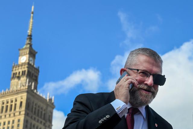 Grzegorz Braun, leader of the Polish far-right and monarchist party "Confederation of the Polish Crown" and serving member of the European Parliament speaks on a mobile phone in front of the Palace of Culture and Science as he attends the signature collection campaign calling for the recall of Warsaw Mayor Rafal Trzaskowski and the Warsaw City Council in Warsaw on August 20, 2026. (Photo by Sergei GAPON / AFP)