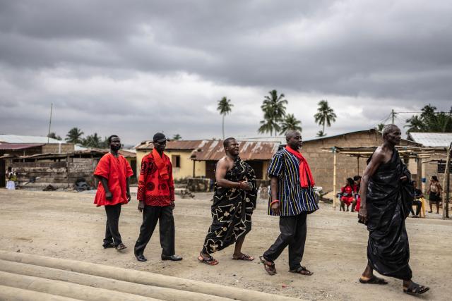 Mourners arrive to attend the funeral ceremony of the late Ghanaian teacher Samuel Commey Tetteh in Paanor, Ghana, on August 15, 2026. Fantasy coffins are a distinctive Ghanaian funerary tradition, particularly associated with the Ga people of the Greater Accra region. Known locally as abebuu adekai (“proverb boxes”), they are handcrafted in the shape of objects, animals or vehicles reflecting the deceased’s profession, personality or interests — from a fish for a fisherman to a shoe for a footballer. Developed around Accra in the mid-20th century, the tradition has evolved into a highly skilled craft. The practice reflects a Ghanaian approach to funerals in which mourning can coexist with celebration, symbolism and a strong emphasis on remembering the life and identity of the deceased. (Photo by OLYMPIA DE MAISMONT / AFP)