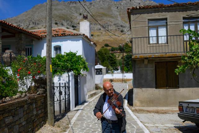 Timoleon Cakni, a 86 years old resident plays a violin on Gokceada (Imroz) Island, Çanakkale Province of Turkey, on August 16, 2026. Hundreds of Greeks return from Athens and around the world to Imbros each August 15 to celebrate the Virgin Mary. Like Istanbul and nearby Tenedos, the island was exempt from the 1923 population exchange between Greece and Turkey, which displaced more than 1.5 million people. (Photo by Yasin AKGUL / AFP)