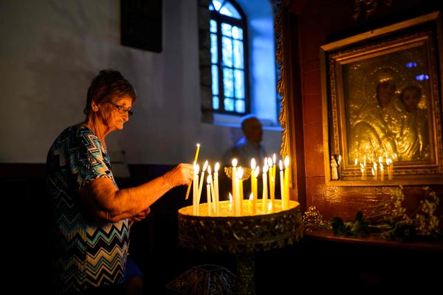 A woman light a candle during the Feast of the Dormition of the Virgin Mary at the Evangelismos Teotoku church on Gokceada (Imroz) Island, Çanakkale Province of Turkey, on August 14, 2026. Hundreds of Greeks return from Athens and around the world to Imbros each August 15 to celebrate the Virgin Mary. Like Istanbul and nearby Tenedos, the island was exempt from the 1923 population exchange between Greece and Turkey, which displaced more than 1.5 million people. (Photo by Yasin AKGUL / AFP)