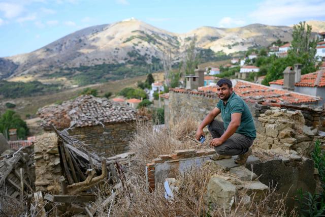 A man living in Tepekoy poses in front of a landscape during the Feast of the Dormition of the Virgin Mary, on Gokceada (Imroz) Island, Çanakkale Province of Turkey, on August 15, 2026. Hundreds of Greeks return from Athens and around the world to Imbros each August 15 to celebrate the Virgin Mary. Like Istanbul and nearby Tenedos, the island was exempt from the 1923 population exchange between Greece and Turkey, which displaced more than 1.5 million people. (Photo by Yasin AKGUL / AFP)