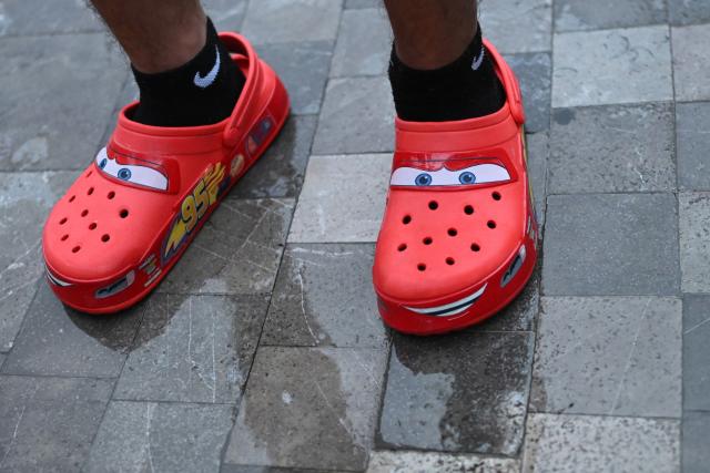 The clogs depicting the Disney character "Lightning McQueen" of Kaled Rosales Salazar (16), winner of the first "Batalla de Aura," are pictured as he speaks during an interview in front of the Palace of Fine Arts in Mexico City on August 20, 2026. The so-called "Aura Battle" is a new viral trend among young people in which two individuals face off in public spaces without speaking, using poses, walks, or dance moves to demonstrate who projects more charisma and style. (Photo by Yuri CORTEZ / AFP)