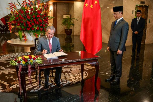 Indonesian Foreign Minister Sugiono (2nd R) watches as Chinese Foreign Minister Wang Yi signs the guest book prior to the Comprehensive Strategic Dialogue meeting at the Ministry of Foreign Affairs in Jakarta on August 21, 2026. (Photo by BAY ISMOYO / AFP)
