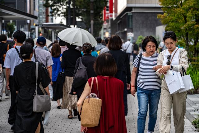 Pedestrians walk at the Ginza shopping district in Tokyo on August 21, 2026. (Photo by Philip FONG / AFP)