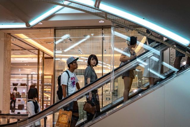 People ride an escalator in a shopping mall at the Ginza district in Tokyo on August 21, 2026. (Photo by Philip FONG / AFP)