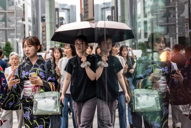 Pedestrians walk at the Ginza shopping district in Tokyo on August 21, 2026. (Photo by Philip FONG / AFP)