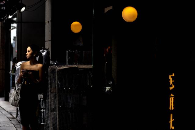 A woman stands in front of a shop at the Ginza shopping district in Tokyo on August 21, 2026. (Photo by Philip FONG / AFP)