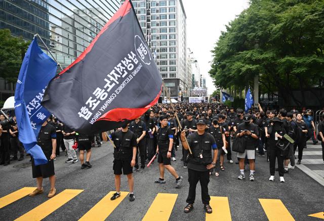 Members of the Samsung Electronics Company Union hold flags during a rally demanding compensation negotiations in front of the Samsung Electronics Seocho building in Seoul on August 21, 2026. (Photo by Jung Yeon-je / AFP)