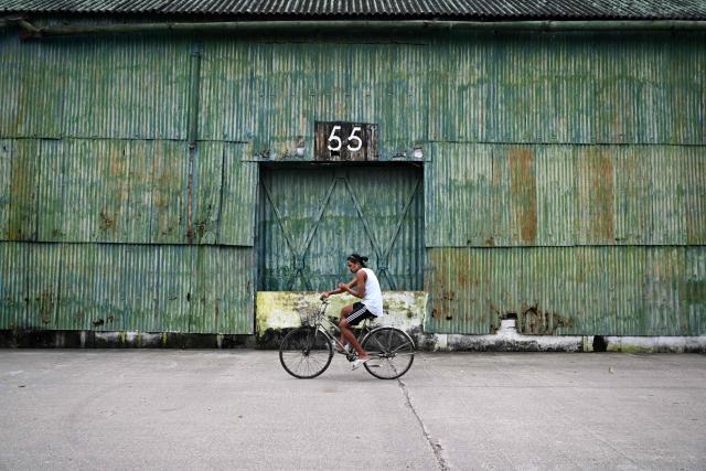A man rides a bike past a warehouse in Yangon on August 21, 2026. (Photo by SAI AUNG MAIN / AFP)