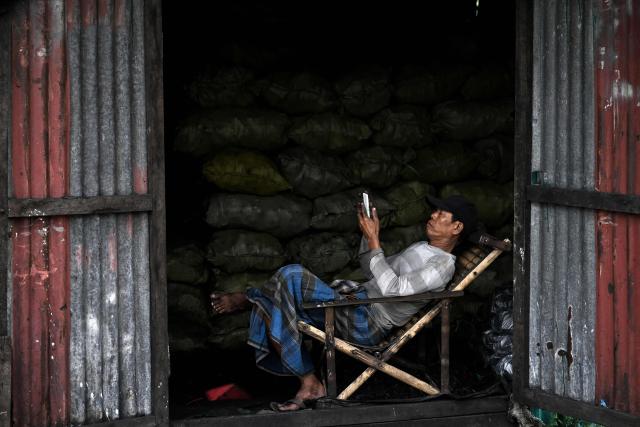 A man walks past a large green corrugated iron warehouse wall in Yangon on August 21, 2026. (Photo by SAI AUNG MAIN / AFP)
