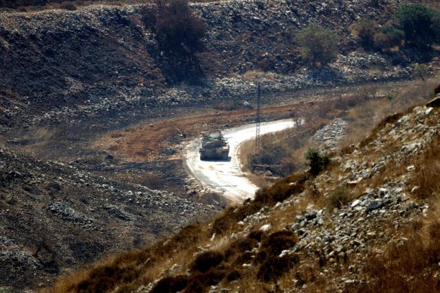 A photograph taken from the southern Lebanese village of Chaqra shows an armoured Israeli vehicle driving through the nearby area of Wadi al-Slouki on August 21, 2026. Hezbollah drew Lebanon into the broader Middle East war in March 2026, with rocket fire at Israel in support of its backer Iran. Israel responded with a heavy air campaign and ground invasion that Lebanese authorities say have killed more than 4,300 people. (Photo by Ammar Ammar / AFP) / 