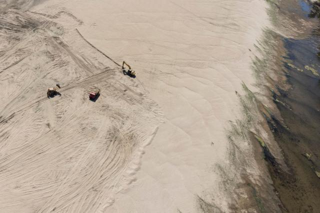 This aerial photograph shows excavators digging sand from the bottom of a dried-up branch of the Danube River near the city of Ruse, on August 21, 2026. The Danube -- which runs from the Black Forest mountains of western Germany through 10 countries to the Black Sea -- has dropped to record low levels in parts due to prolonged rain shortages and successive heatwaves since May 2026. (Photo by Nikolay DOYCHINOV / AFP)