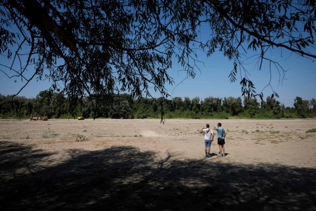 People walk along the dried river bed of the Danube River near the city of Ruse on August 21, 2026. The Danube -- which runs from the Black Forest mountains of western Germany through 10 countries to the Black Sea -- has dropped to record low levels in parts due to prolonged rain shortages and successive heatwaves since May 2026. (Photo by Nikolay DOYCHINOV / AFP)