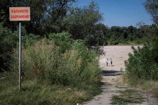 People walk along the dried river bed of the Danube River near the city of Ruse on August 21, 2026. The Danube -- which runs from the Black Forest mountains of western Germany through 10 countries to the Black Sea -- has dropped to record low levels in parts due to prolonged rain shortages and successive heatwaves since May 2026. (Photo by Nikolay DOYCHINOV / AFP)
