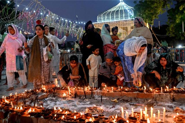 Devotees light candles and earthen lamps to mark the 'Urs' or death anniversary of the Sufi saint Mian Mir at his shrine in Lahore on August 21, 2026. (Photo by Arif ALI / AFP)