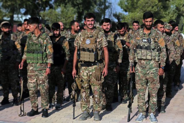 Kurdish fighters from the Qamishli Brigade, part of the Syrian Democratic Forces (SDF) participate in a military parade in Qamishli on August 21, 2026, during the funeral ceremony for three Kurdish fighters killed in previous battles in Aleppo's Sheikh Maqsoud neighbourhood in the north of Syria. (Photo by Delil SOULEIMAN / AFP)