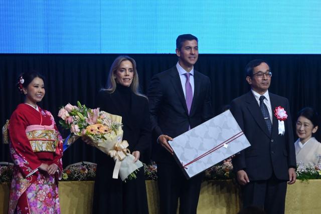 Japan's Crown Princess Kiko (R, behind) looks as Paraguay's President Santiago Pena (C) and his wife Leticia Ocampos (2-L), receive presents from the Japanese community in Paraguay during the commemoration of the 90th anniversary of the Japanese immigration in the country, at the Conmebol headquarters in Luque, Paraguay, on August 21, 2026. (Photo by DANIEL DUARTE / AFP)