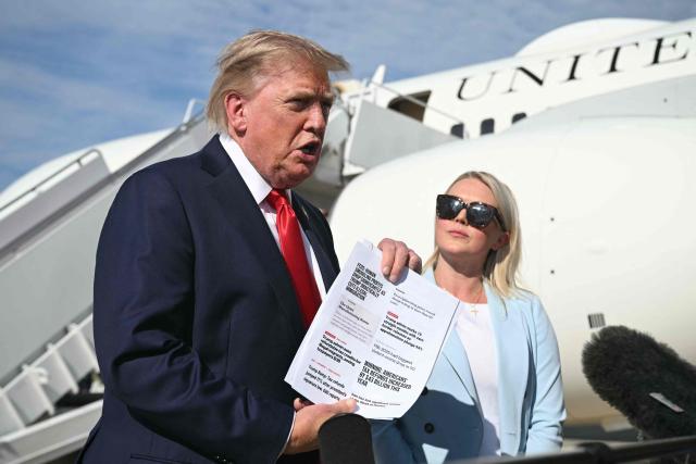 US President Donald Trump, flanked by White House Press Secretary Karoline Leavitt, holds a document as he speaks to reporters before boarding Air Force One at Joint Base Andrews, Maryland on August 21, 2026. Trump is headed to Myrtle Beach, South Carolina to attend a campaign rally for US Senator Darline Graham. (Photo by SAUL LOEB / AFP)