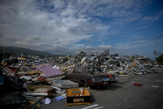 An abandoned car is seen amid piles of debris in Catia La Mar, La Guaira state, Venezuela, on August 21, 2026, two months after earthquakes of magnitudes 7.2 and 7.5 struck the area. (Photo by Federico PARRA / AFP)