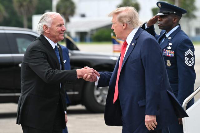 US President Donald Trump shakes hands with South Carolina Governor Henry McMaster after disembarking from Air Force One upon arrival at Myrtle Beach International Airport in Myrtle Beach, South Carolina, on August 21, 2026. Trump is traveling to attend a campaign rally for US Senator Darline Graham. (Photo by SAUL LOEB / AFP)