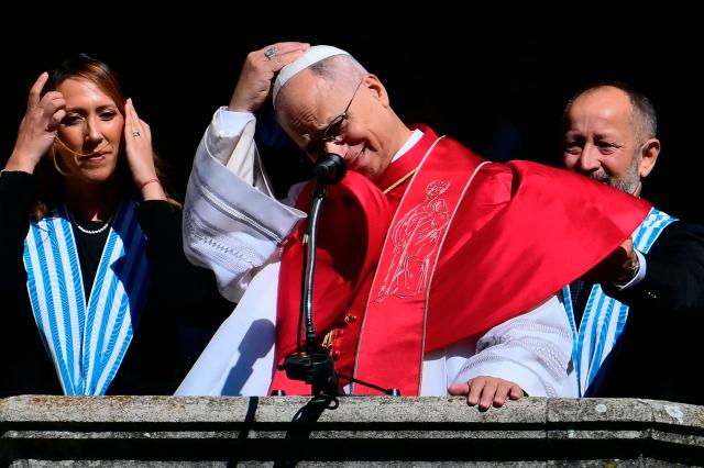 Pope Leo XIV, flanked by San Marino's Captains Regent Alice Mina and Vladimiro Selva, greets the crowd from the balcony of the Public Palace during a pastoral visit to San Marino on August 22, 2026. (Photo by Stefano RELLANDINI / AFP)