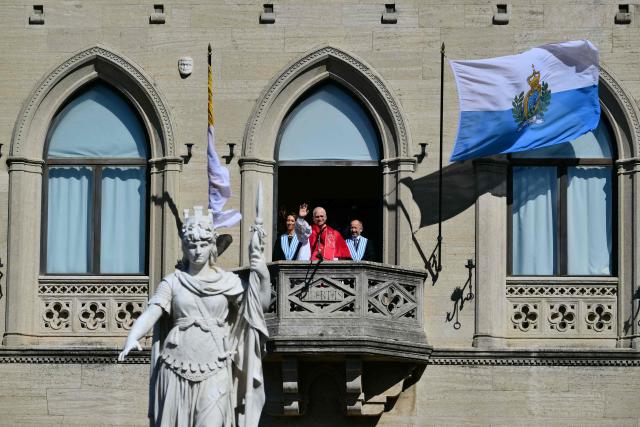 Pope Leo XIV, flanked by San Marino's Captains Regent Alice Mina and Vladimiro Selva, greets the crowd from the balcony of the Public Palace during a pastoral visit to San Marino on August 22, 2026. (Photo by Stefano RELLANDINI / AFP)