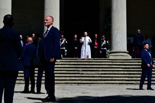 Security staff members stand guard as Pope Leo XIV greets the crowd outside San Marino's basilica during a pastoral visit on August 22, 2026. (Photo by Stefano RELLANDINI / AFP)
