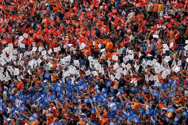 (FILES) Fans wave coloured flags prior to the start of the Dutch Formula One Grand Prix race at The Circuit Zandvoort, in Zandvoort on August 27, 2023. For three days a year, the quiet residential street of Van Speijkstraat in the sleepy Dutch beach resort of Zandvoort transforms itself into a sea of orange streamers and chequered flags, welcoming Formula One fans from around the world. (Photo by SIMON WOHLFAHRT / AFP)