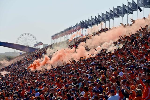 (FILES) Fans burn orange flares during the drivers' parade at the Zandvoort circuit before the start of the Netherlands' Formula One Grand Prix in Zandvoort on September 5, 2021. For three days a year, the quiet residential street of Van Speijkstraat in the sleepy Dutch beach resort of Zandvoort transforms itself into a sea of orange streamers and chequered flags, welcoming Formula One fans from around the world. (Photo by ANDREJ ISAKOVIC / AFP)