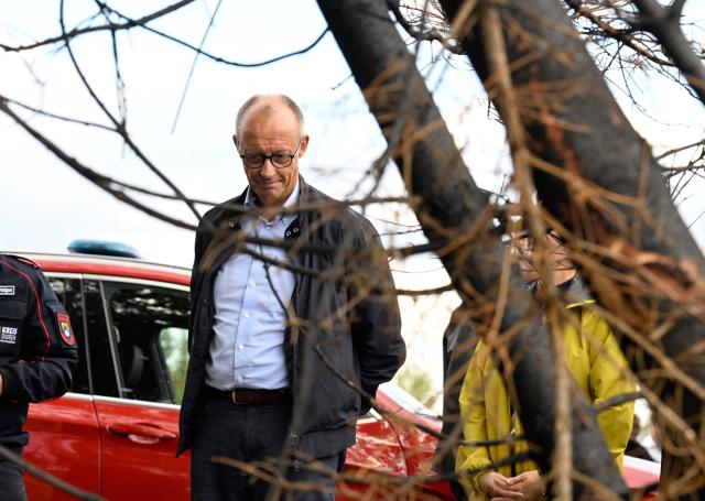 German Chancellor Friedrich Merz visits an area affected by a devastating wildfire in Huertgenwald, western Germany, on August 22, 2026. Parts of the municipality near the Belgian border were evacuated last week after the blaze spread from 25 hectares (about 60 acres) to 300 hectares, temporarily displacing about 1,800 residents. Following the devastating wildfire, Merz visited the region to thank emergency responders and assess the situation on the ground. (Photo by Roberto Pfeil / POOL / AFP)