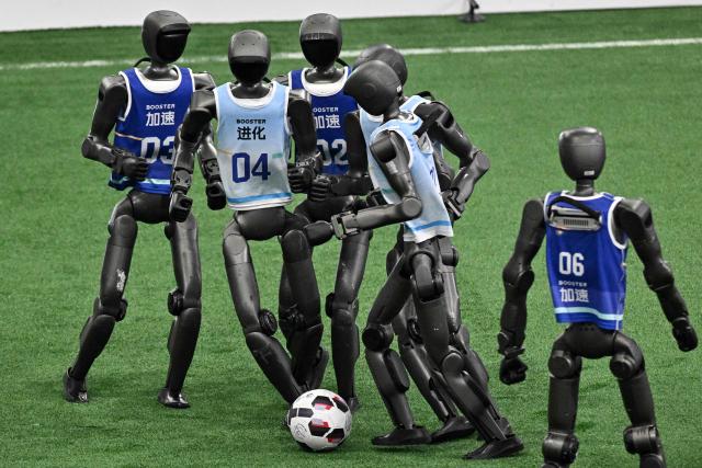 Humanoid robots vie for the ball during a football match at the 2nd World Humanoid Robot Games in Beijing on August 22, 2026. (Photo by Pedro PARDO / AFP)