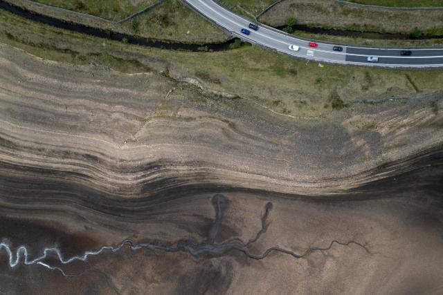 An aerial photograph shows the partially revealed bed of Woodhead Reservoir following a falling water level, near Glossop, northern England on August 22, 2026. Nearly three quarters of England has been classified as in drought after the driest July on record. (Photo by Oli SCARFF / AFP)