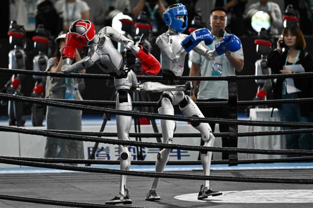 Humanoid robots fight during a kickboxing match at the 2nd World Humanoid Robot Games in Beijing on August 22, 2026. (Photo by Pedro PARDO / AFP)