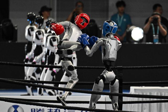 Humanoid robots fight during a kickboxing match at the 2nd World Humanoid Robot Games in Beijing on August 22, 2026. (Photo by Pedro PARDO / AFP)