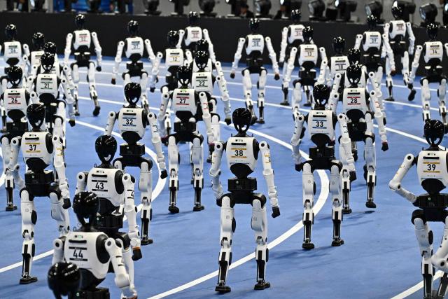 Humanoid robots take part in the opening ceremony of the 2nd World Humanoid Robot Games in Beijing on August 22, 2026. (Photo by Pedro PARDO / AFP)