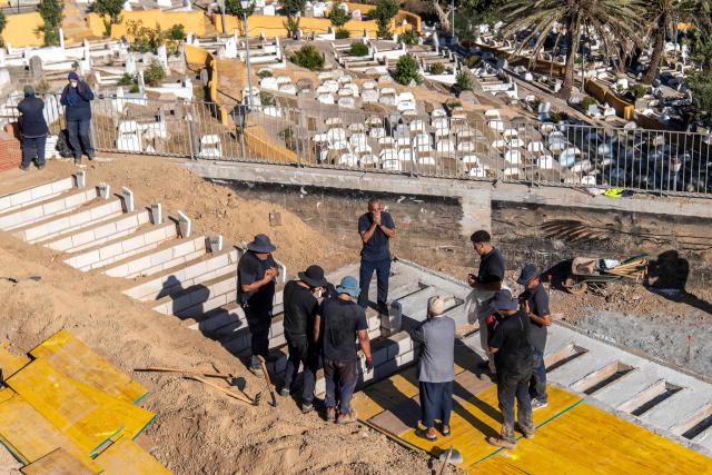 A group of people prays during the burial of some of the unidentified migrants who drowned while trying to swim to the Spanish coast of Ceuta from the Moroccan coast, in Ceuta, on August 22, 2026. Some 72,000 migrants breached the border in an unprecedented and deadly rush into the north African territory on July 30-31, with 70,000 having since returned to Morocco, according to Spanish government figures. (Photo by Antonio Sempere / AFP)