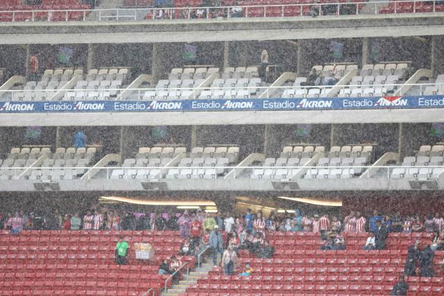 Guadalajara's fans take shelter from the rain as the delayed start of the Liga MX Apertura football match between Guadalajara and Tijuana in Zapopan, Jalisco, Mexico on August 22, 2026. (Photo by ULISES RUIZ / AFP)