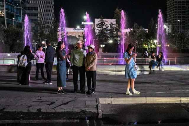 People stand in a park in the center of Ulaanbaatar on August 22, 2026. (Photo by Hector RETAMAL / AFP)