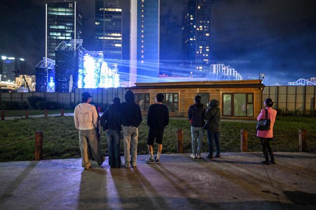 People watch a concert from outside the closed perimeter of the show in Ulaanbaatar early on August 23, 2026. (Photo by Hector RETAMAL / AFP)