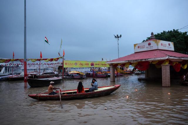 People travel by boat through the flooded Assi Ghat along the Ganges River in the early morning hours in Varanasi on August 23, 2026. (Photo by Niharika KULKARNI / AFP)