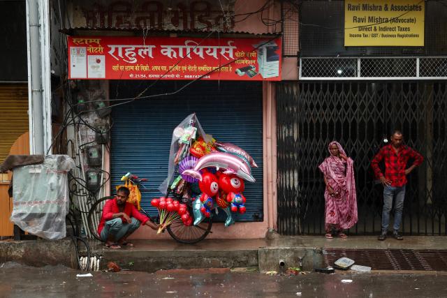 People take shelter under a pavement amid rainfall during the early morning hours in Varanasi on August 23, 2026. (Photo by Niharika KULKARNI / AFP)