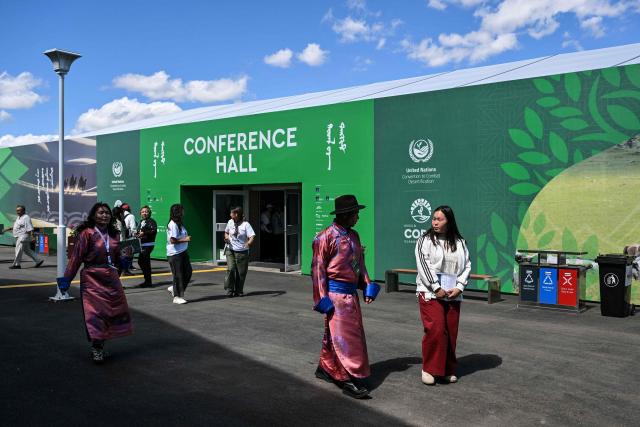 People walk outside the conference hall ahead of the 17th Session of the Conference of the Parties (COP17) of the United Nations Convention to Combat Desertification (UNCCD) at the venue in Ulaanbaatar on August 23, 2026. (Photo by Hector RETAMAL / AFP)