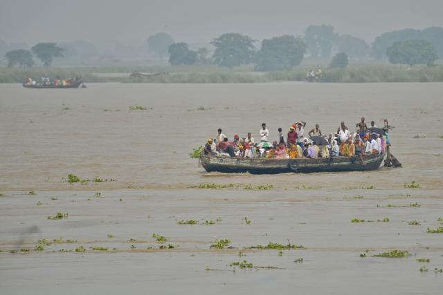 Flood-affected residents along with their belongings move to a safer place by boat as the water level of the Ganges rises following heavy rains in Patna on August 23, 2026. (Photo by Sachin KUMAR / AFP)