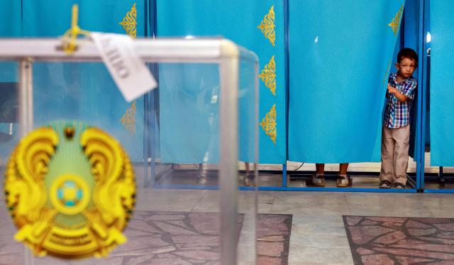 A boy looks on from the polling booth as his parent casts a ballot at a polling station during parliamentary elections, in Almaty, southeastern Kazakhstan on August 23, 2026. Ex-Soviet Kazakhstan votes for a new unicameral parliament following changes to its constitution that authorities say will democratise Central Asia's largest economy, but critics slam the move as cementing the president's power. (Photo by Ruslan PRYANIKOV / AFP)